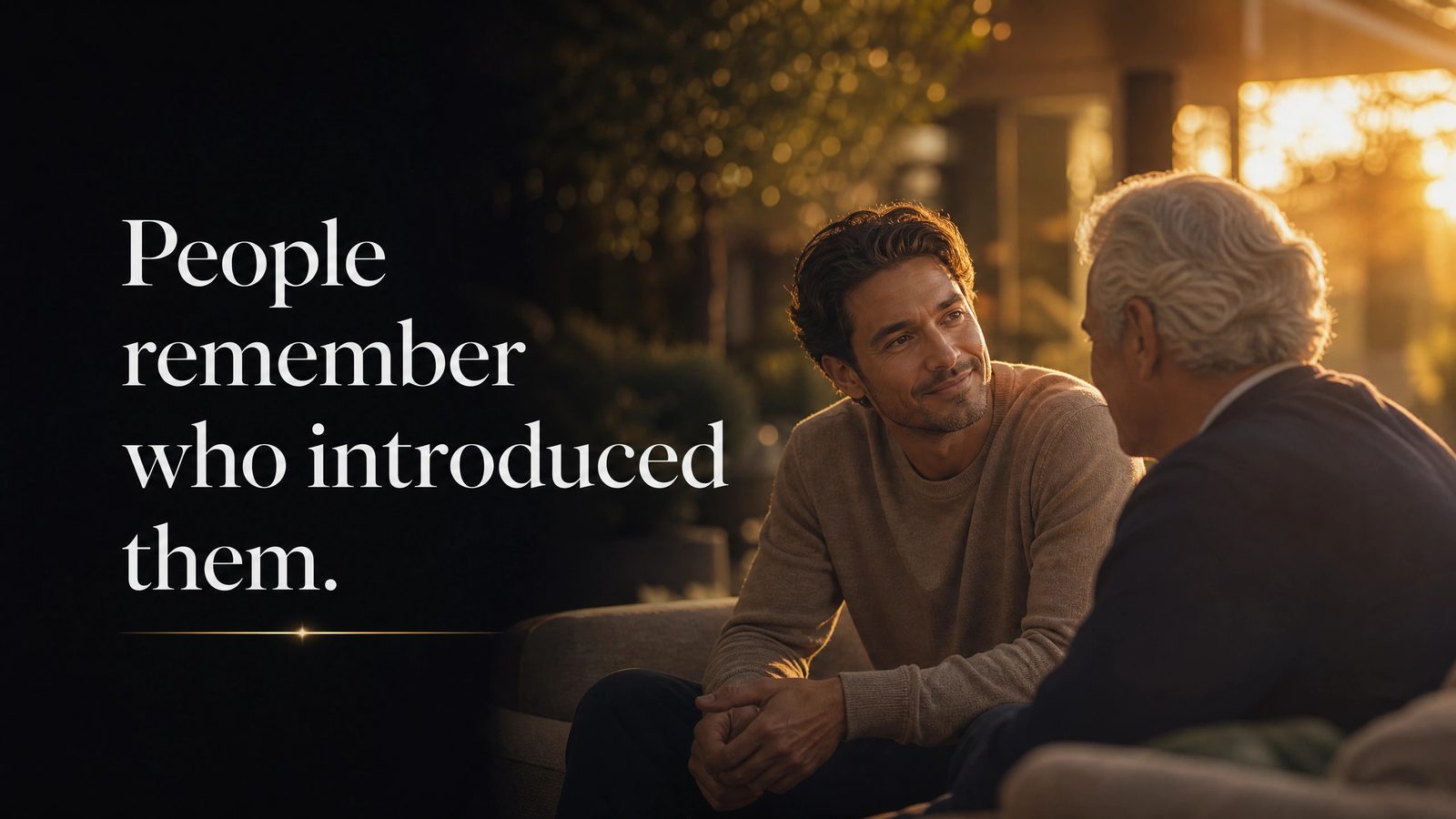 A younger man in warm golden-hour conversation with a silver-haired man on an outdoor sofa